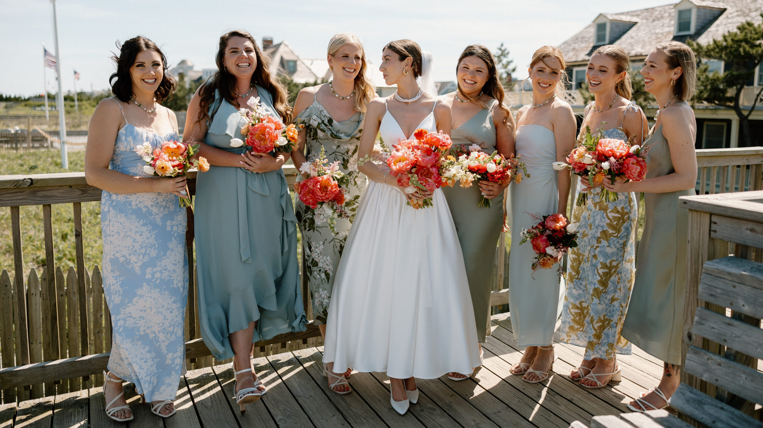 Bride and Bridesmaids holding bouquets of peonies showcasing bright corals with soft pink and orange accents