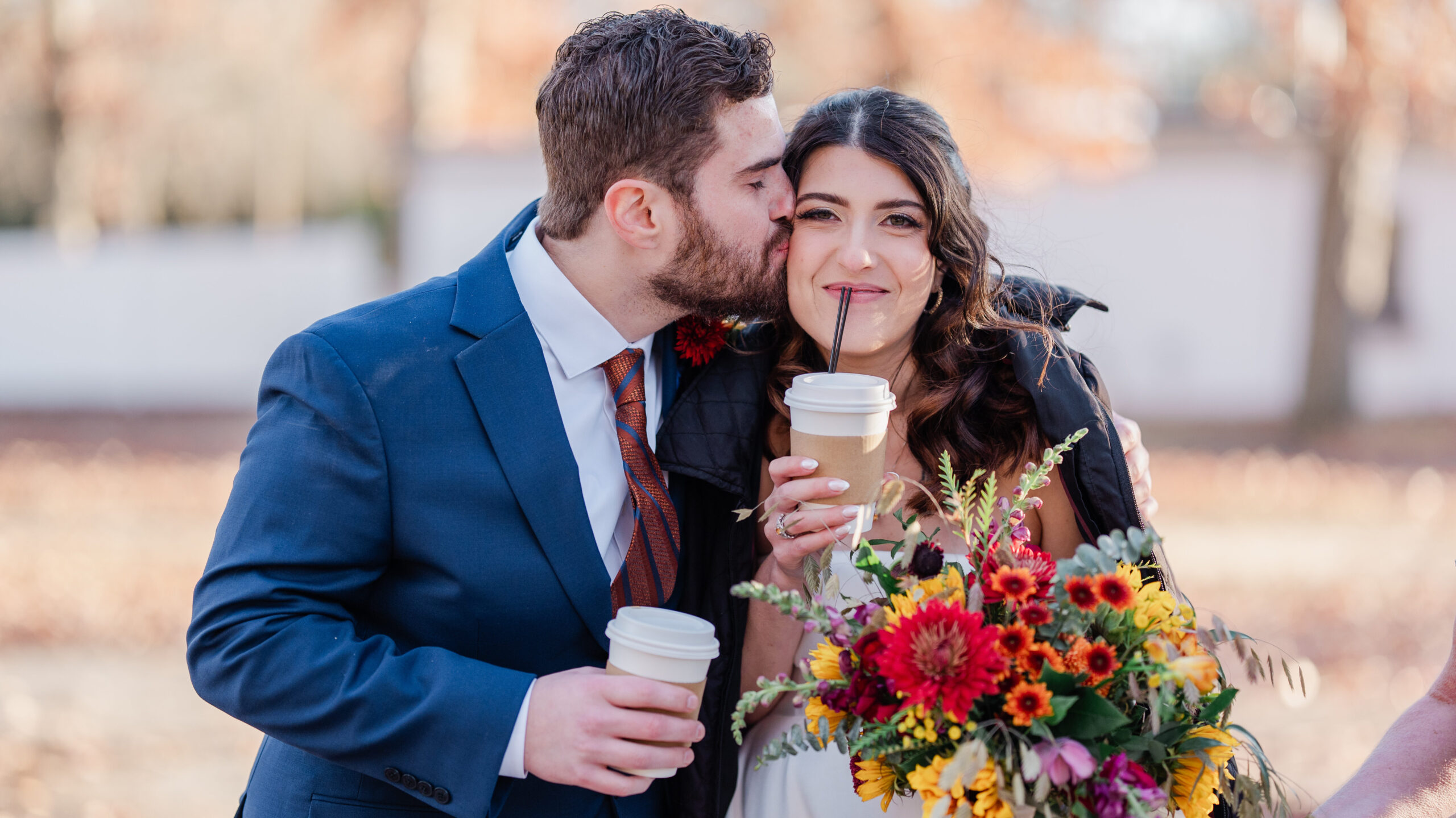 Bride and Groom sipping coffee. Bride holding a vibrant colored wedding bouquet of dahlias, zinnia's and golden yellow hypericum berries
