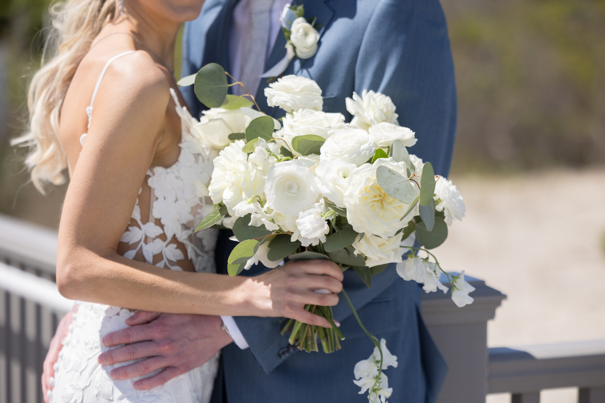 White bridal bouquet and floral design featuring roses, ranunculus, and eucalyptus, crafted by Leigh Florist for a wedding at ICONA Windrift.